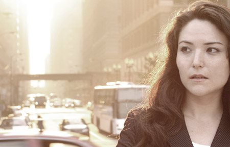 Woman in a city with traffic behind her.