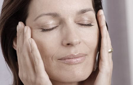 Middle-aged woman holding her face with both hands.