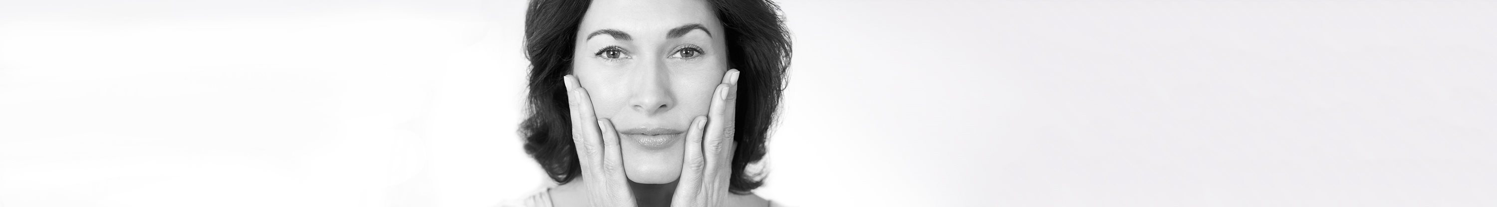 Middle-aged woman touching her cheeks with both hands.