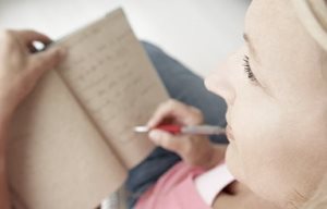 Woman is writing something in her note pad.