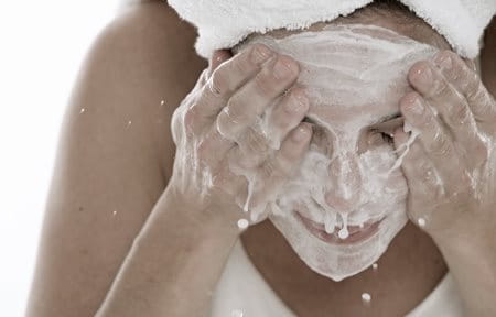 Woman washing her face to protect skin barrier