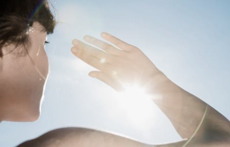 Woman protects her face from the sun with her hand