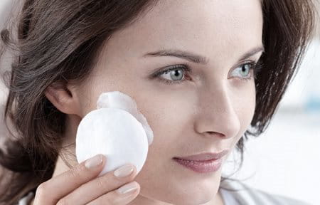 Woman cleansing her face with cotton pad
