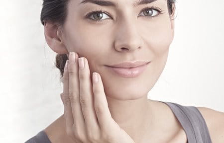 Woman applying cream on her face to hydrate skin
